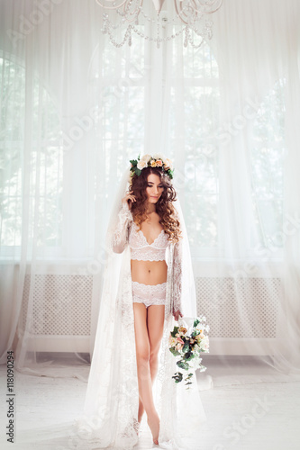 Fotótapéta sexy bride standing on a white light hall dressed in nighty, bridal veil and wre