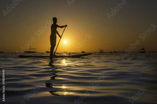 Silhouette of man paddling on paddle board at sunset.