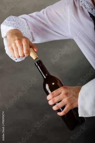 Waiter opens wine bottle.