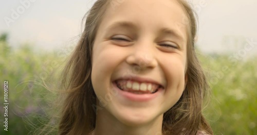 Smiling portrait of beautiful girl with long hair looking at camera in garden