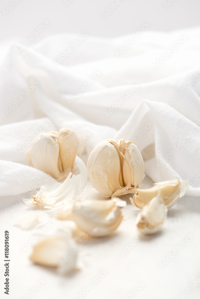 multiple cloves of garlic scattered over white cutting board multiple cloves of garlic scattered over white cutting board