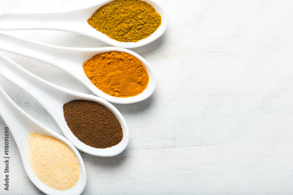 colorful spices in white spoons with copy space, overhead view colorful spices in white spoons with copy space, overhead view
