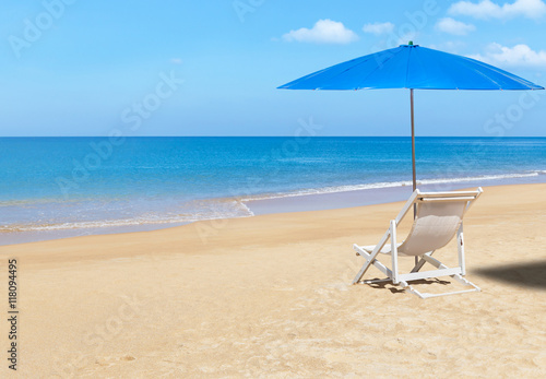 Fototapeta Naklejka Na Ścianę i Meble -  white wooden beach chair and blue parasol on tropical beach in sunny day.