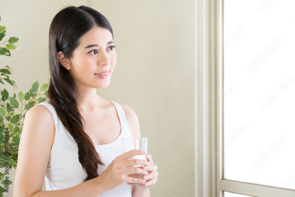 Beautiful asian woman looking out of window and drinking water Beautiful asian woman looking out of window and drinking water
