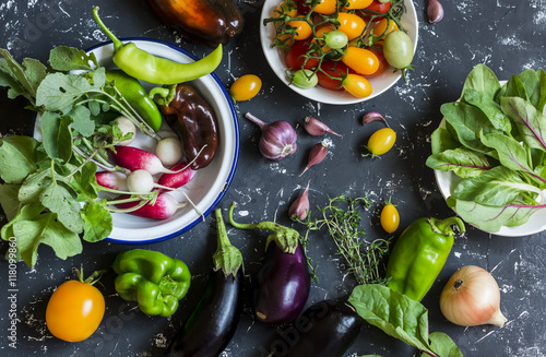 Fotografie Fresh vegetables - radishes, eggplant, pepper, tomatoes, onion, garlic on a dark wooden background