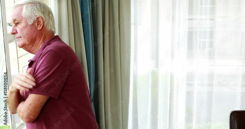A retired person thinking while looking through the window in retirement home A retired person thinking while looking through the window in retirement home