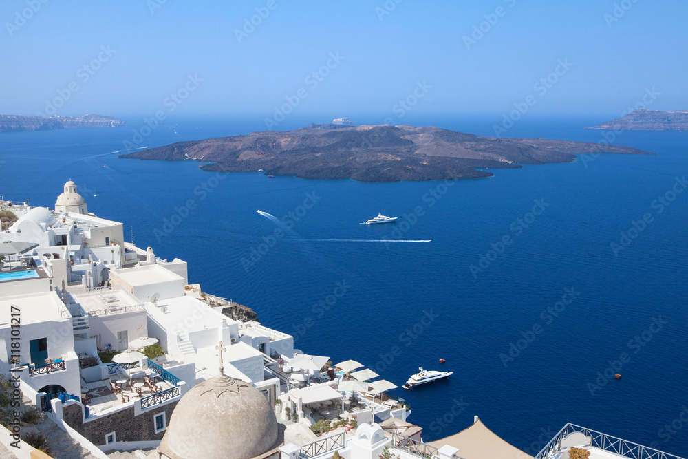 Fototapeta premium White houses of Fira, Santorini with Santorini's famous volcano in the background