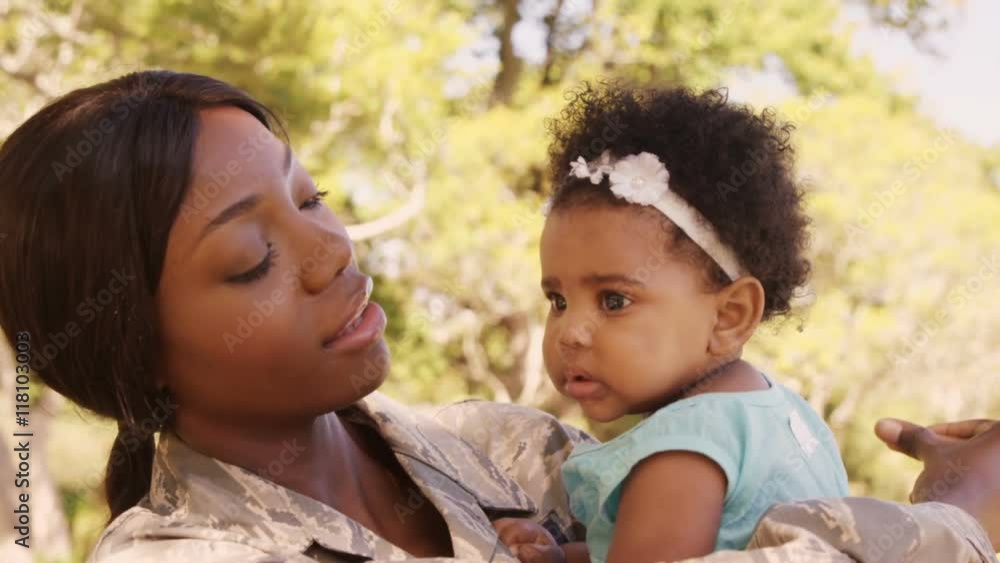 Soldier mother holding her daughter in a park Soldier mother holding her daughter in a park