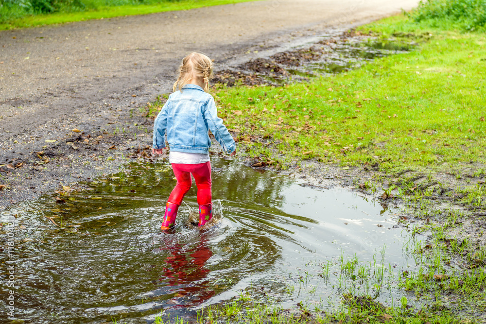 Little girl with red boots splashing in the puddle Little girl with red boots splashing in the puddle