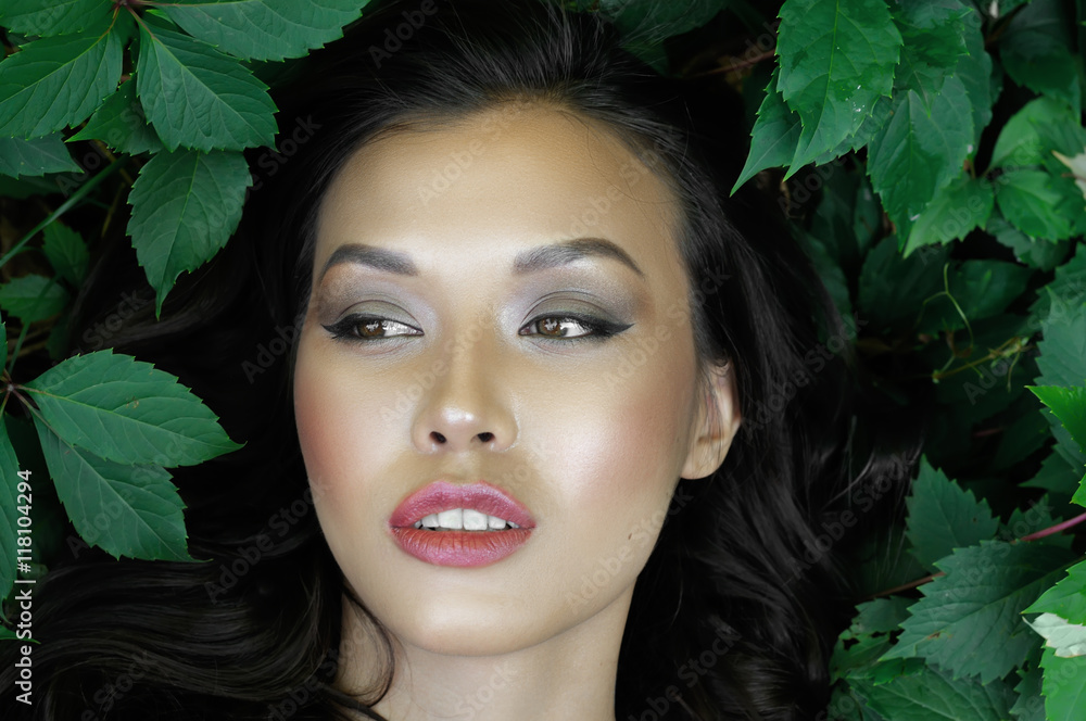 Fototapeta premium Girl lying in the green foliage