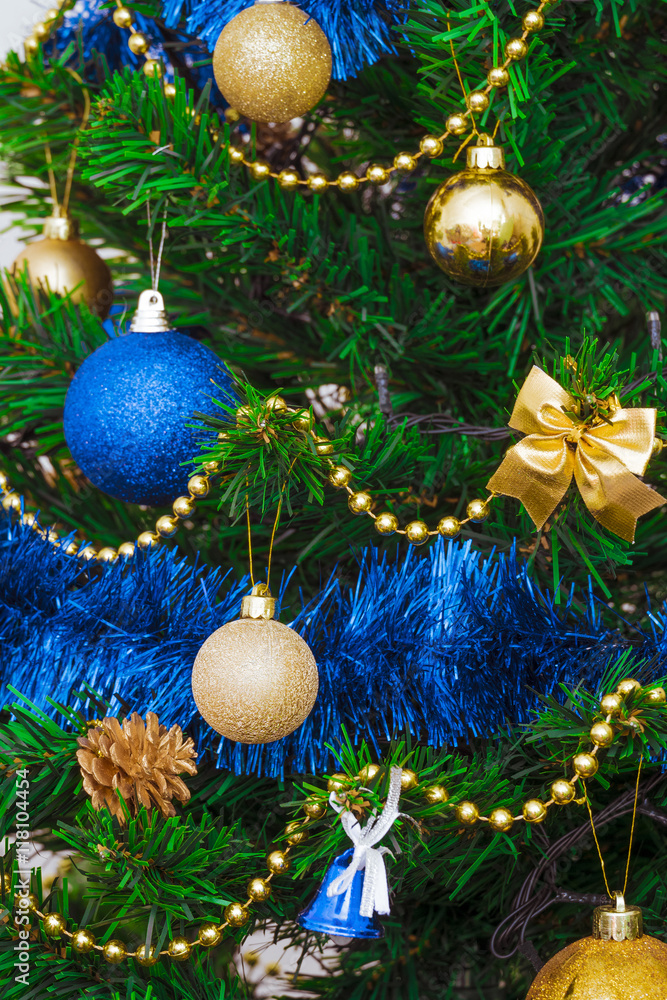 Christmas decorations on a green artificial fir. Golden and bright blue on a green background. Fragment. Photo with limited depth of field.