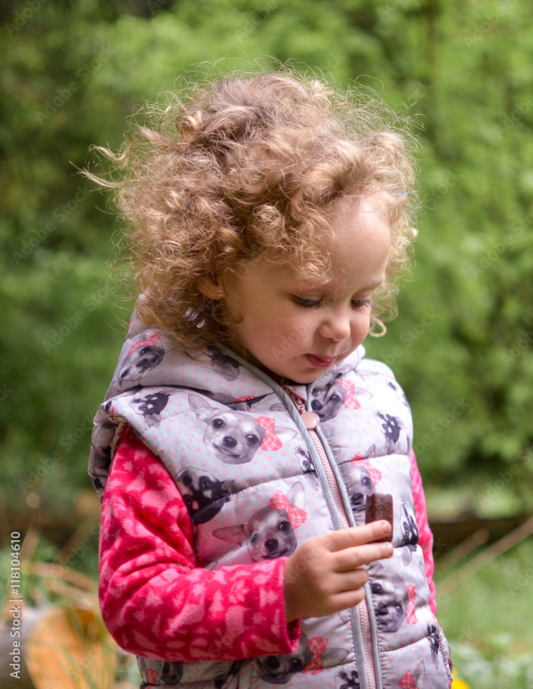 girl child eating candy in the park girl child eating candy in the park