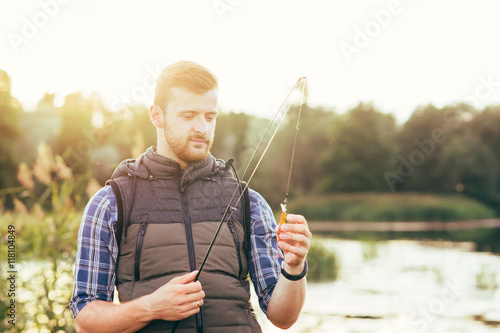 Fisherman with a spinning rod and bait (lure, wobbler)  catching © Acronym