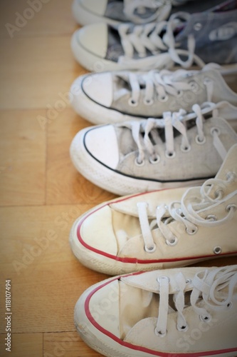 Several pairs of vintage sneakers with different colors and style on a wood floor.