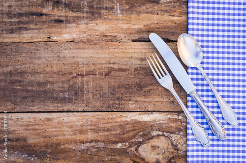 Rustic food background with checked tablecloth fork, knife and spoon 