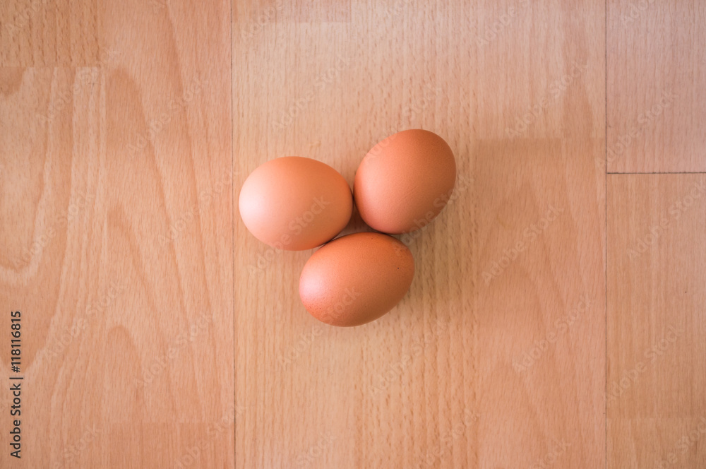 Group of three hen egg on wooden table/ floor background