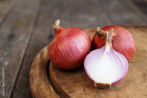 Close up of sliced and whole red onion on a wooden table.
