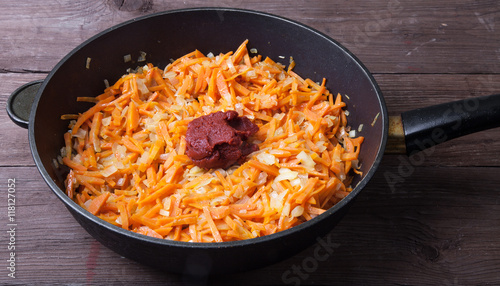 Chopped carrots and onions with tomatoes paste in a frying pan f
