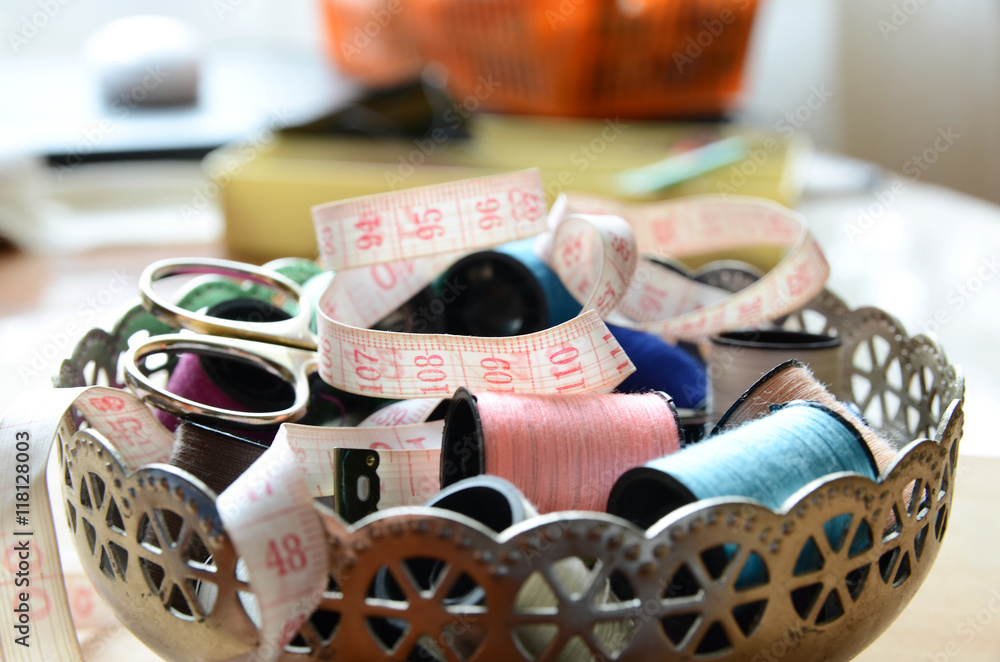 Sewing accessories: scissors, centimeter, bobbins with thread and needles on metal vintage bowl. Sewing accessories: scissors, centimeter, bobbins with thread and needles on metal vintage bowl.