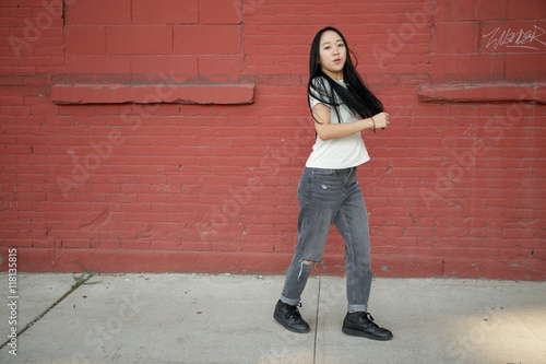 Young Asian woman in city dancing hip hop