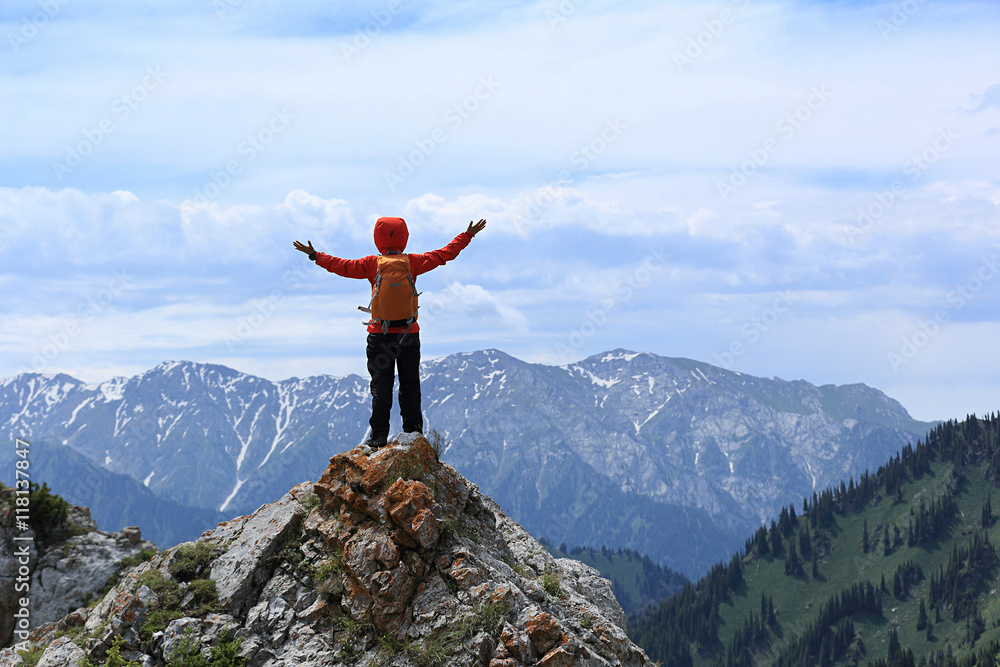 Fototapeta premium successful young woman backpacker open arms on mountain peak