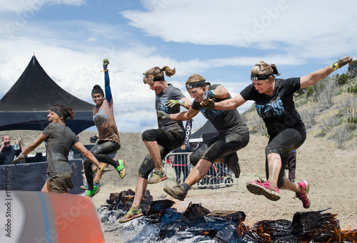 Spartan Race, Fort Carson, CO May 2015
Five women competitors jumping over fire to the finish line with enthusiastic supporter.

