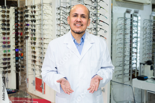 Male optician near stand with glasses.