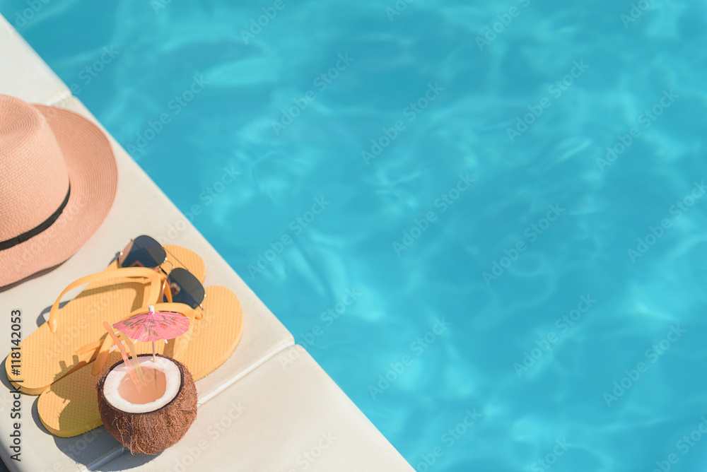 Obraz premium Flip flops with cocktail and sunglasses near pool