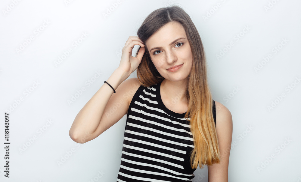 Portrait of happy young beautiful woman in striped shirt touching her hair posing for model tests against studio background Portrait of happy young beautiful woman in striped shirt touching her hair posing for model tests against studio background