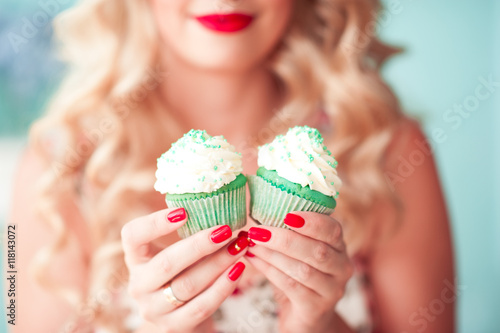 Woman holding two cupcakes with cream cheese in room closeup