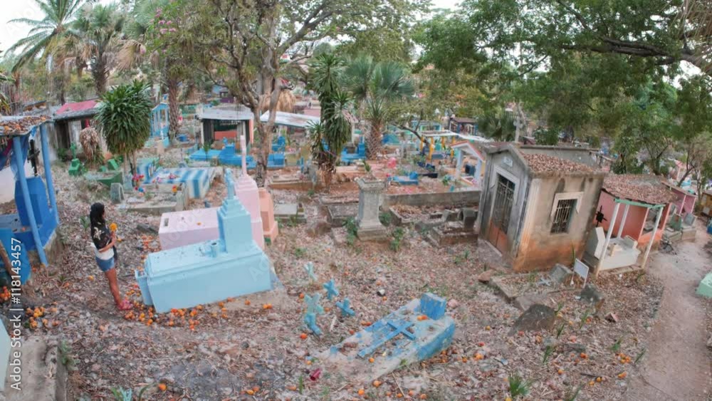 Hispanic woman leaving flowers on grave at the cemetery of Tapachula