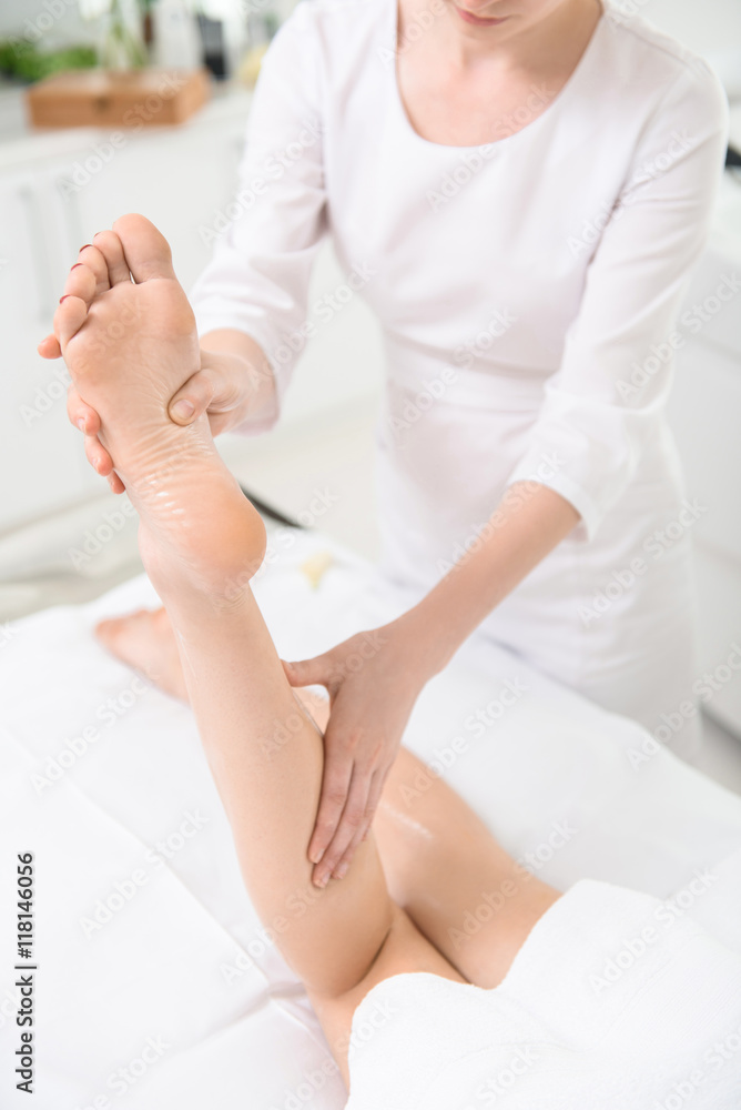Skillful beautician massaging human foot