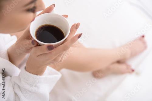 Cute girl drinking beverage in bathrobe