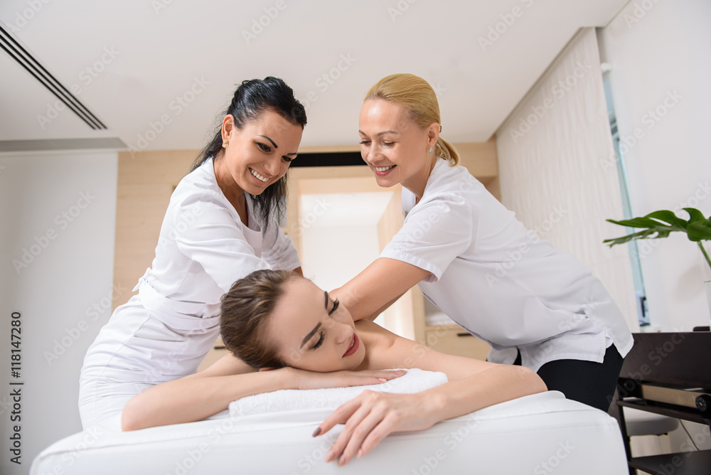 Fototapeta premium Skillful beauticians massaging female back