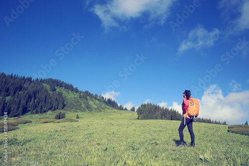 young woman backpacker hiking on beautiful mountain peak