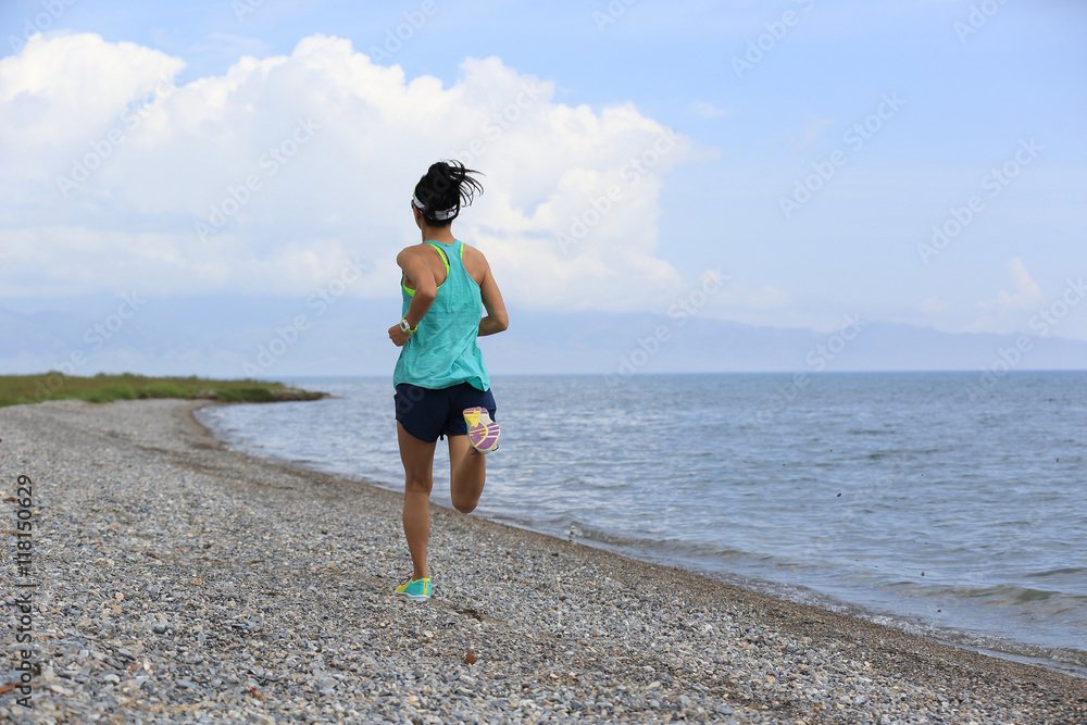 healthy young woman trail runner running on seaside