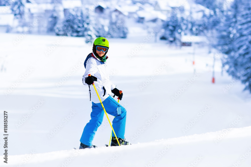 Child skiing in mountains. Active teen age kid with safety helmet, goggles and poles. Ski race for young children. Winter sport for family. Kids ski lesson in alpine school. Skier racing in snow