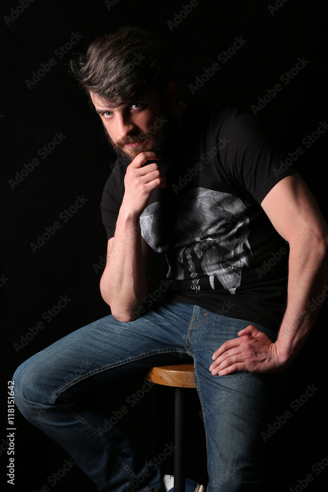 Bearded guy sitting on a bar stool and holding his chin . Close.up. Black