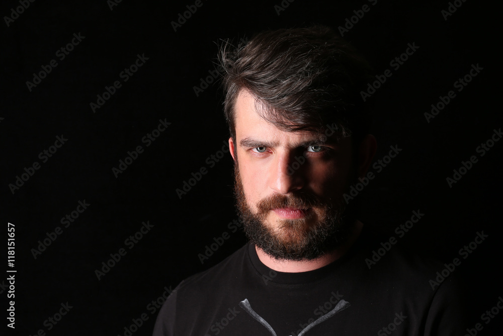Bearded man in T-shirt with serious look. Close.up. Black