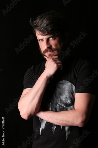 Bearded man with serious look holding his chin. Close.up. Black © kazanovskyiphoto