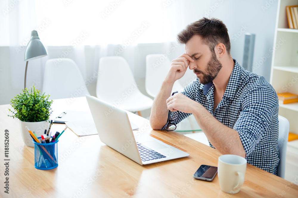 Overworked young man thinking about way to complete task Overworked young man thinking about way to complete task