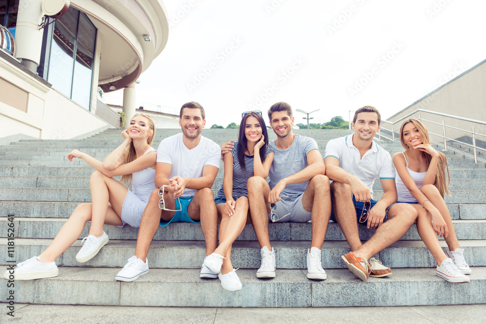 joyful diverse best friends embracing and sitting on stairs whil joyful diverse best friends embracing and sitting on stairs whil