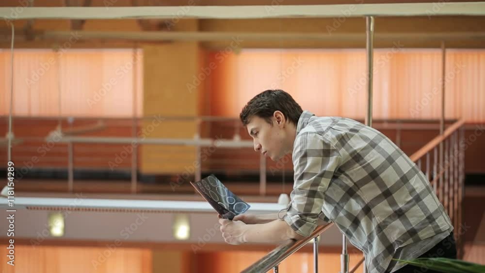 Attractive man stands in hall relying on metal railing. Attractive man stands in hall relying on metal railing.