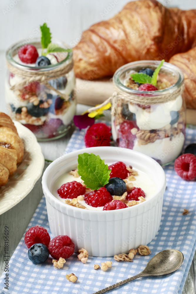 Breakfast table: bowl of yogurt with muesli and fresh fruits Breakfast table: bowl of yogurt with muesli and fresh fruits