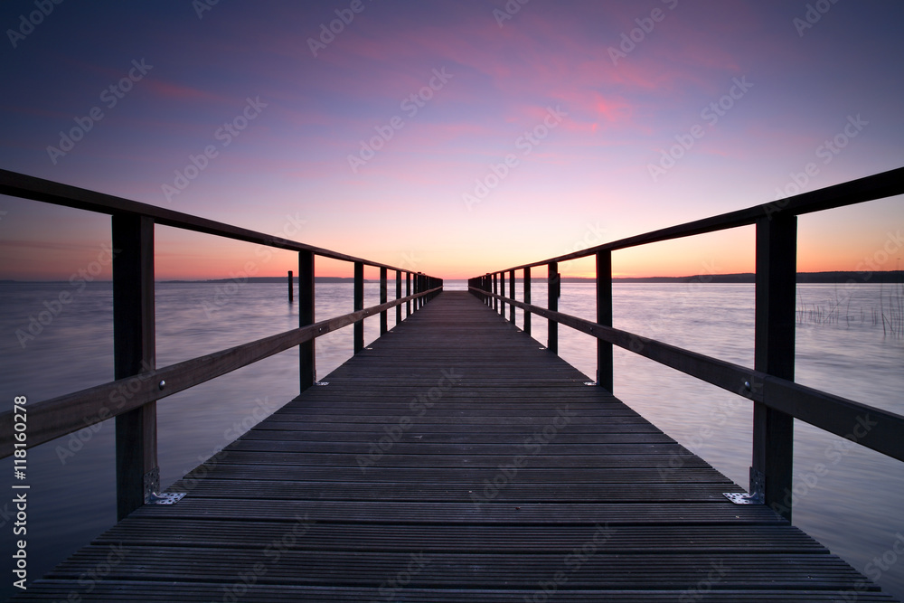 Long Wooden Pier into a Lake at Sunset, perfect symmetry