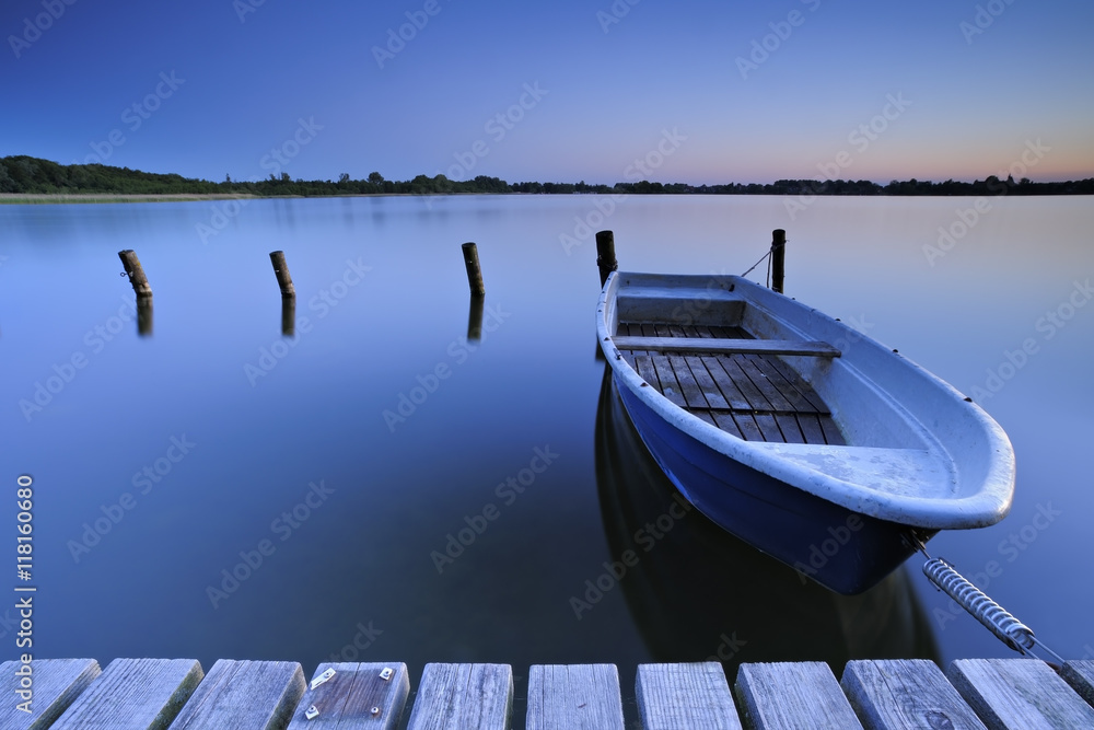 Obraz premium Calm Lake at Sunrise, Fishing Boat Tied to Wooden Pier