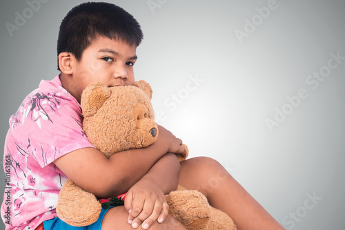 Little boy sad alone with brown teddy bear