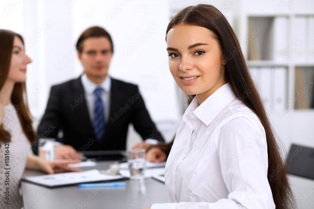 Portrait of a young business woman against a group of business people at a meeting. Portrait of a young business woman against a group of business people at a meeting.
