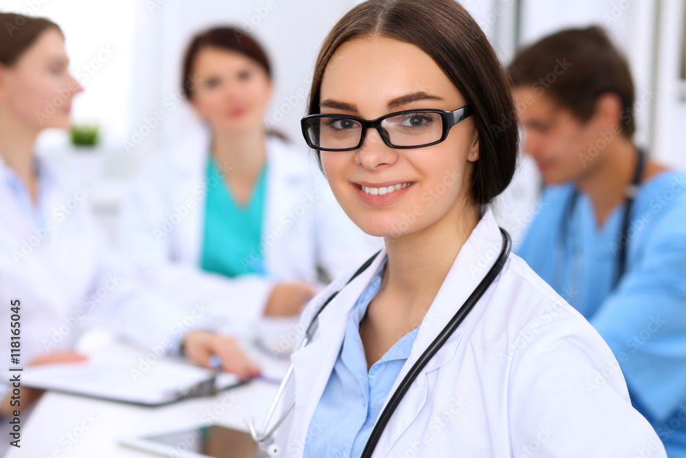 Fototapeta premium Happy doctor woman with medical staff at the hospital sitting at the table and discussing medical history