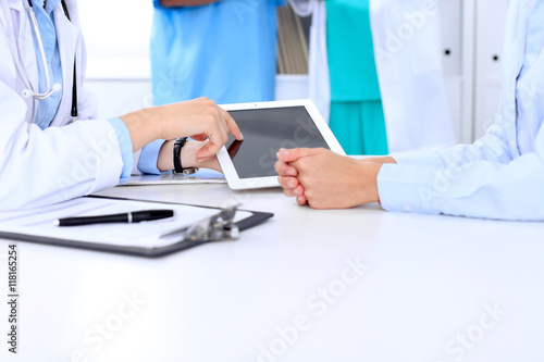 Doctor and patient are discussing something. Physician pointing into tablet computer.